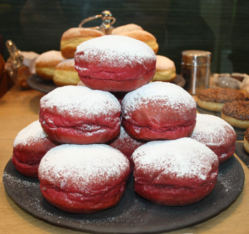 Rote Faschingskrapfen mit Marillenmarmeladenfüllung und Staubzucker. Mit Lebensmittelfarbe gefärbt. Foto GroßHandel Eis GmbH